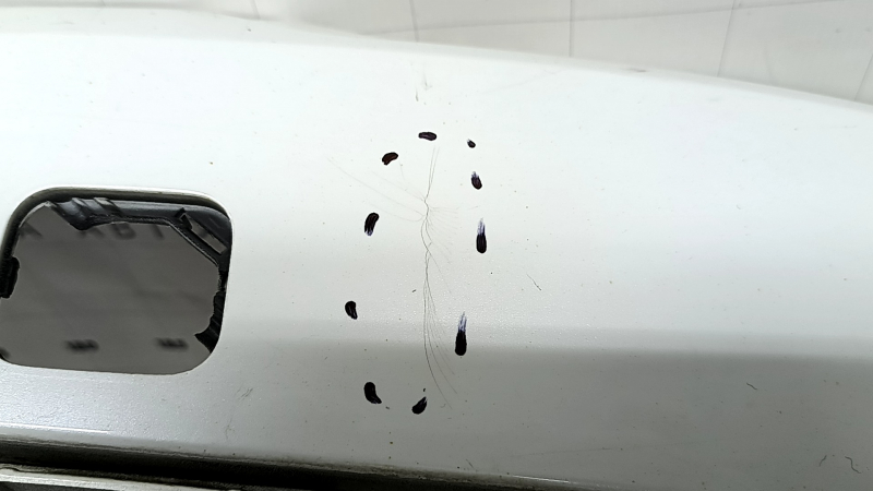 The bare lower rear bumper of a Volvo XC90 16-26 for parking sensors, white, the parking sensor mount is broken, dented, and there are cracks in the mounts.