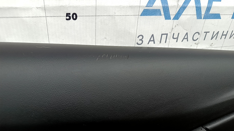 The front left door panel of a Chevrolet Volt 16 is black, with a black leather insert, the armrest is black leather, with a handle, without a trim and buttons, scratches