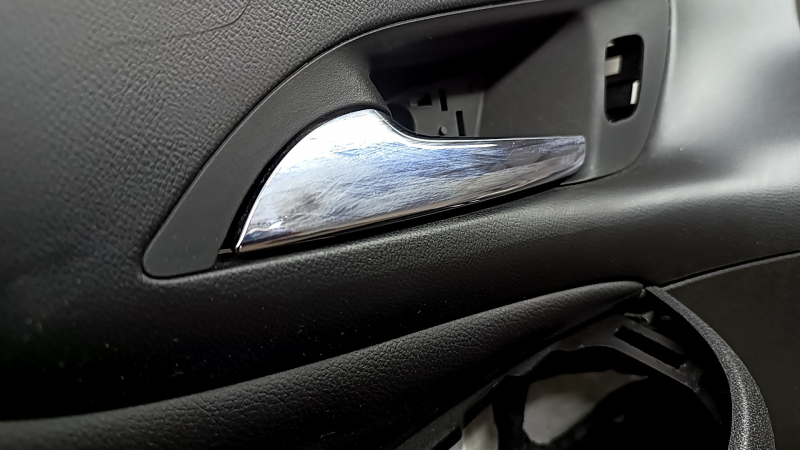 The front left door panel of a Chevrolet Volt 16 is black, with a black leather insert, the armrest is black leather, with a handle, without a trim and buttons, scratches