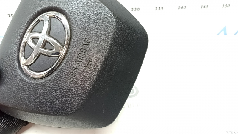 The Toyota Highlander 20-22 driver's steering wheel airbag is black and scratched.