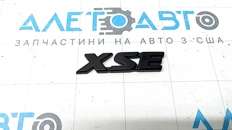The "XSE" emblem on the tailgate of a Toyota Rav4 19-25, gloss black, chipped