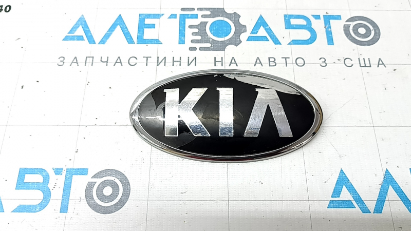 The emblem badge of the front bumper of the Kia Niro 17-22 has peeled off coating and swollen varnish