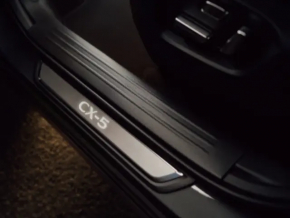 A set of black door sill plates for the Mazda CX-5 17-25 with a chrome insert and backlight, scratches